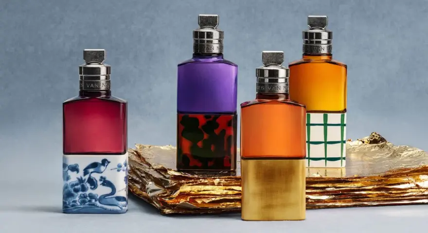 Vier bunte Parfumflaschen mit silbernen Verschlüssen auf goldenem Untergrund.